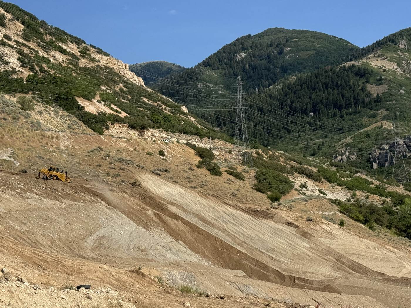 Benched hillside excavation with dozer working the slope